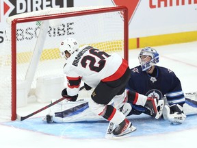 Ottawa Senators defenceman Erik Brannstrom (left) beats Winnipeg Jets goaltender Eric Comrie for a shootout goal during NHL exhibition play at Canada Life Centre in Winnipeg on Sun., Sept. 26, 2021.