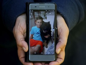 A closeup shows a phone-size photo of one of Christina Kennis' two beloved dogs, Chloe, with her 15-year-old son, Lucas.