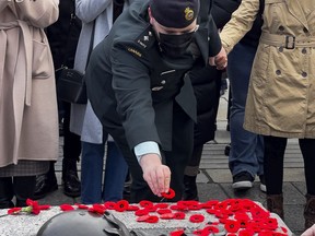 File: A member of the Canadian Armed Forces places a poppy on the Tomb of the Unknown Soldier following Remembrance Day services at the National War Memorial in 2021.