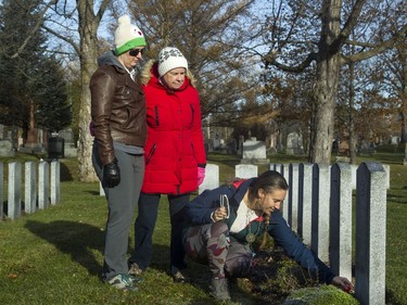 Julia Sharpe places a poppy on the Beechwood Cemetery grave of her grandparents, while her sister, Jessica Elgin, and mother, Barbara Tink, look on.