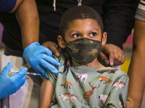 Christopher Reyes, 9, sits silently as he is administered the coronavirus (COVID-19) vaccine at a vaccination pop-up site at P.S. 19 on November 08, 2021 in the Lower East Side in New York City.