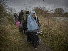 DUNKIRK, FRANCE - NOVEMBER 25: Refugees walk through the new Jungle with their bags and belongings on November 25, 2021 in Dunkirk, France. At least 27 people including five women and a young girl died yesterday trying to cross the Channel to the UK in an inflatable dinghy in an incident which the International Organisation for Migration described as the biggest single loss of life in the Channel since it began collecting data in 2014.