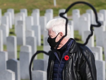 A man walks through the tombstones of fallen soldiers in the National Military Cemetery after the Remembrance Day ceremonies at the National Military Cemetery at the Beechwood Cemetery in Ottawa, November 11, 2021.