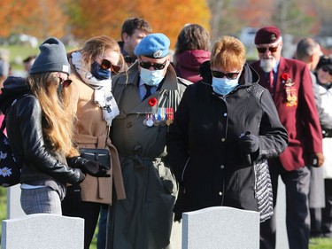 Family members remember a lost member who is buried in the Military Cemetery after the Remembrance Day ceremonies at the National Military Cemetery at the Beechwood Cemetery in Ottawa, November 11, 2021.