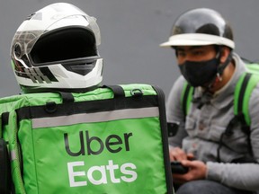 An Uber Eats food delivery courier wearing a protective face mask waits for an order amid the outbreak of the coronavirus disease. REUTERS/Valentyn Ogirenko