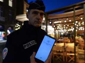 A policeman shows the application he uses to check the COVID-19 health passes during a control operation in bars and restaurants in Saint-Malo, northwestern France, on November 19, 2021.