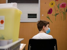 A child, age 11, waits after receiving the Pfizer-BioNTech Covid-19 vaccine for children in Montreal, Quebec on November 24, 2021.
