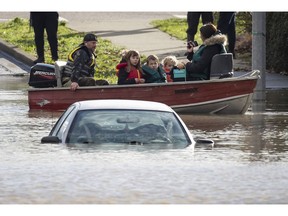 A woman and children who were stranded by high water due to flooding are rescued by a volunteer in Abbotsford, B.C., on Nov. 16.