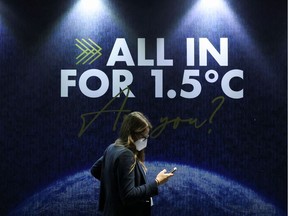 A delegate walks past a sign during the UN Climate Change Conference (COP26) in Glasgow, Scotland, Britain, November 11, 2021.