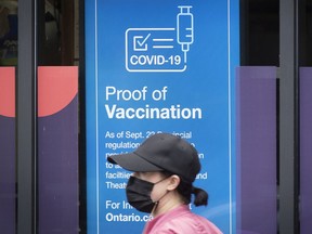A person wears a mask to protect them from the COVID-19 virus while walking past information about vaccination proof in Kingston, Ontario on Thursday September 23, 2021.