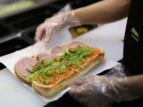 An employee prepares a sandwich inside a Subway fast food restaurant.