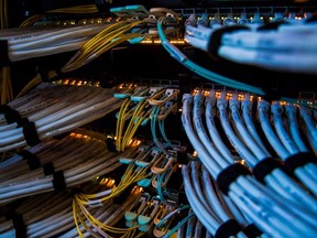 Fiber optic cables and copper Ethernet cables feed into switches inside a communications room.