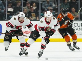 Ottawa Senators' Lassi Thomson, center, moves the puck as he is followed by teammate Connor Brown during the first period of an NHL hockey game against the Anaheim Ducks Friday, Nov. 26, 2021, in Anaheim , Calif.