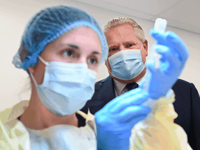 File: Ontario Premier Doug Ford watches a health-care worker prepare a dose of COVID-19 vaccine.