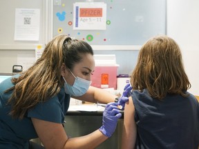 File: A nurse gives a dose of the Pfizer COVID-19 vaccine to a young girl.