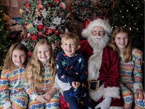 From left to right: Anna Fulton 8, Elise Ravesloot 9, Charlie Fulton 5, and Mary Fulton 12, have their photo taken with Santa in the garage.