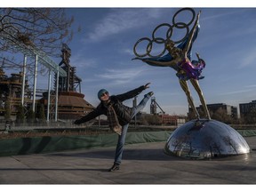 BEIJING — A visitor poses beside a statue showing figure skaters and the Olympic Rings for the Beijing 2022 Winter Olympics and Paralympics.