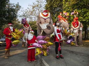 Thai people pose with elephants dressed in Santa Claus costumes on December 24, 2021 in Phra Nakhon si Ayutthaya, Thailand.