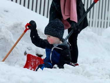 Claire Christie's three-year-old Alec appears to be finished shovelling as he plonks himself down in a snowbank while the pair were out clearing their driveway and path in front of their Manotick home Monday morning.
