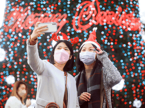 Women take selfies in front of a Christmas tree during the first day of Christmasland, a Christmas theme event at a commercial area in New Taipei City, Taiwan, December 3, 2021.