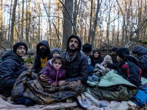 Members of a Kurdish family from Iraq are seen in a forest near the Polish-Belarus border while waiting for the border guard patrol, near Narewka, Poland, on Nov. 9.