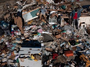 TOPSHOT - In this aerial image: Bogdan Gaicki rests in the rubble of his home as family members help sort through the tornado damage after extreme weather hit the region December 12, 2021, in Mayfield, Kentucky. -