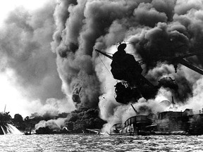 (FILES) This December 7, 1941 file photo obtained from the US Naval Historical Center shows the USS Arizona, sunk and burning furiously.  Her forward magazines had exploded when she was hit by a Japanese bomb. Shown at (L), are men on the stern of USS Tennessee as they move fire hoses on the water to force burning oil away from their ship.