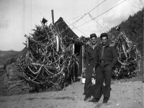 Sapper George Imlay (right), 57th Independent Field Squadron, poses before Christmas decorations at his camp, Korea, 1951.
