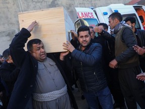 People carry one of the coffins of Iraqi Kurdish migrants who drowned while trying to cross the channel between France and Britain, in the town of Rania, Sulaimaniyah province, Iraq, December 26, 2021.