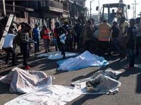 Police and firefighters cover up the bodies of people who were killed after a fuel truck exploded in a neighbourhood during the night, in Cap Haitien, Haiti December 14, 2021.