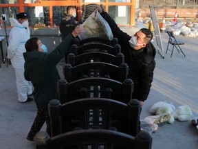 A worker delivers food supplies to residents at a residential compound under lockdown following the coronavirus disease (COVID-19) outbreak in Xian, Shaanxi province, China December 29, 2021.