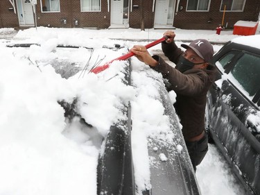 Sam Belui clears the snow and ice off his van after an overnight winter storm in Ottawa Monday