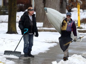 Don Fugler walks his kayak  toward the Rideau River while Pavbel Kratina shovels snow and slush out of his driveway Thursday. Don was going to go skiing Thursday but due to the warm weather he grabbed his kayak and headed for the river.