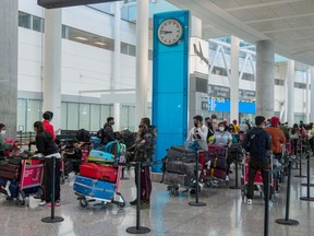 Passengers from New Delhi wait in long lines for transportation to their quarantine hotels at Pearson Airport in Toronto on Friday April 23, 2021.