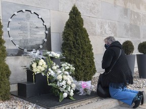 Files: A woman kneels in front of the commemorative plaque on the wall of Polytechnique in Montreal, Sunday, Dec. 6, 2020, on the 31st anniversary of the murder of 14 women in an anti-feminist attack at Ecole Polytechnique on December 6, 1989.