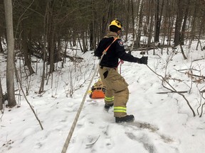 An Ottawa Fire Services crew member guides a "sked" bearing an injured hiker along a trail in the South March Highlands Conservation Forest on Wednesday.