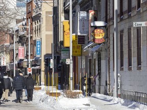 People walk on de La Gauchetière St. in Montreal's Chinatown Sunday Jan. 23, 2022. Quebec's culture and communications ministry announced Monday that parts of Chinatown, including this block, will be classified as a heritage district, protecting it from developers.