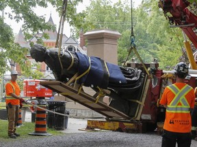 Workers in Kingston remove a statue of Sir John A. Macdonald from the pedestal in City Park and place it on a flatbed. Vandalism of a sign in Annie Pootoogook park reminds us of the complex issues around commemorating historic figures in public places, a letter writer says.