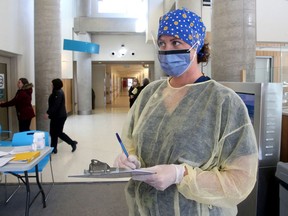 File: A nurse assesses people for possible signs of COVID-19 as they enter Queensway Carleton Hospital's main entrance.