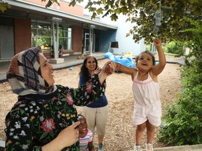 Education assistant Awand Mageed, left,  helps Jaeda play with a bell at Ottawa's Andrew Fleck Child Care Centre in June, 2020. Daycares have remained open in Ontario throughout much of the COVID-19 pandemic.