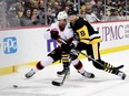 Zach Sanford (13) of the Ottawa Senators and Brian Dumoulin (8) of the Pittsburgh Penguins compete for the puck during the first period at PPG PAINTS Arena in Pittsburgh, Pennsylvania  on Thursday.