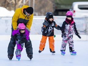 Alexandre Lamoureux helps daughter Clara, 4, skate as siblings Tyler, 9, and Romane, 5, follow along at the Rink of Dreams next to Ottawa City Hall on Friday.