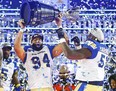 Winnipeg Blue Bombers Jackson Jeffcoat, left, and Jermarcus Hardrick hold up the Grey Cup in Hamilton. File photo