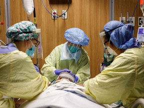 A respiratory therapist adjusts ventilator tubes as health-care workers reposition a patient suffering from COVID-19 at Humber River Hospital's Intensive Care Unit in April 2021.