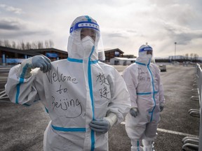 A man poses with the sentence: 'Welcome to Beijing' written on his hazmat suit in Yanqing, which will  host the alpine skiing and sliding venues for the Beijing Winter Olympics.