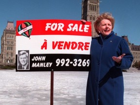File photo/ Federal NDP Leader Alexa McDonough displays a sign that likens Minister John Manley to a real estate salesman on Parliament Hill, Tuesday, March 30, 1999.