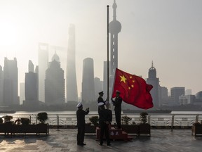 China Customs officers raise a Chinese flag during a rehearsal for a flag-raising ceremony along the Bund in front of buildings in the Lujiazui Financial District at sunrise in Shanghai.