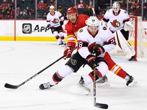 Ottawa Senators forward Connor Brown (28) battles for the puck with Calgary Flames forward Trevor Lewis (22) during the first period at Scotiabank Saddledome, Jan. 13, 2022.