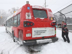 Jen Mayhew is trying to help push a stuck OC Transpo bus out onto Carleton Avenue in Ottawa on Monday.
