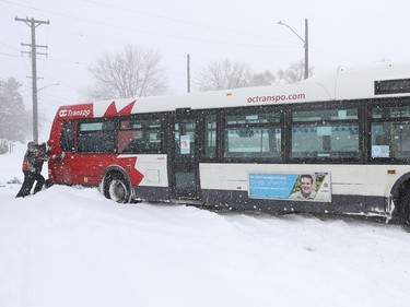 OTTAWA - Jan 17 2022  Jen Mayhew and her son Brayden try to help push out a stuck OC Transpo bus on Carleton Ave. in Ottawa Monday.